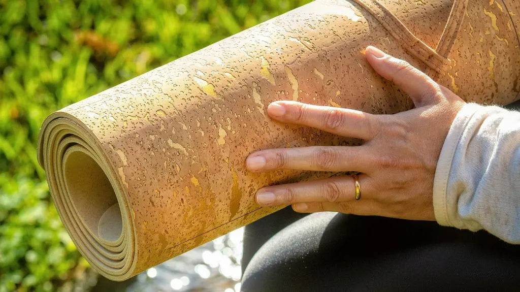 Hand hält aufgerollte Yogamatte aus Kork im Freien – Beispiel für wie wird Kork geerntet und genutzt